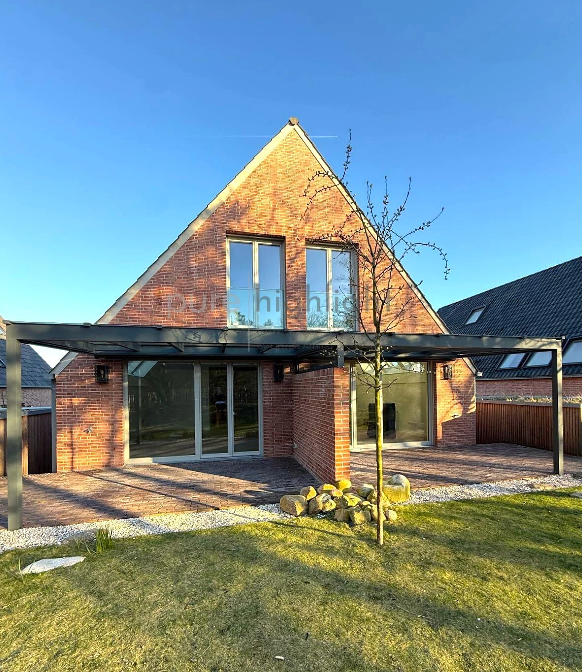 Gartenfassade mit gläserner Terrassenüberdachung und Rasenfläche