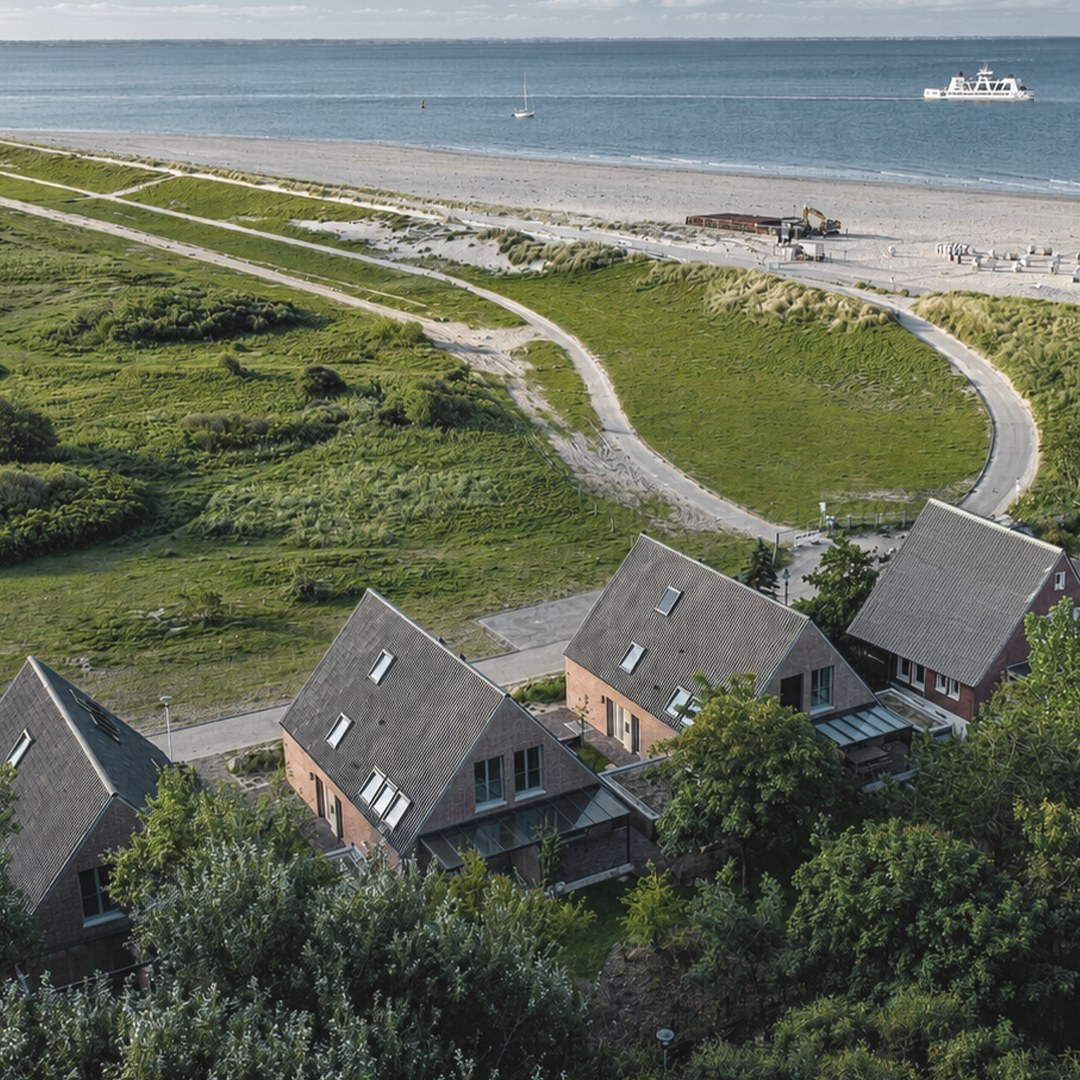 Luftbild: das Ensemble am Dünenrand, dahinter Weststrand und Nordsee